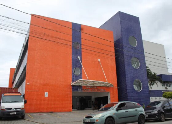 Imagem do Hospital Regional do Litoral, com fachada colorida em tons de laranja e roxo, destaque para a entrada e veículos estacionados. Governo investe R$ 5,1 milhões para reforçar atendimento no Hospital Regional do Litoral