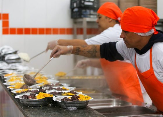 Cozinheiros servindo comida nas marmitas
