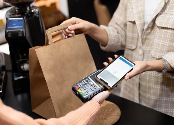 Imagem mostra pessoa usando o smartphone para pagar comprar; comércio, varejo